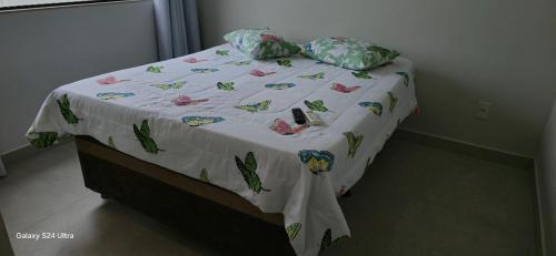 a bed with a white comforter and pillows on it at Casa Temporada Sereia do Mar in São Mateus