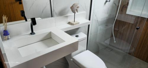 La salle de bains blanche est pourvue d'une douche et de toilettes. dans l'établissement Casa Temporada Sereia do Mar, à São Mateus