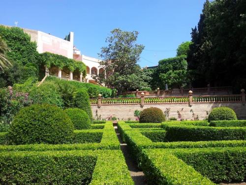 a garden with trimmed hedges and a building at Casa Victor Riu in Piera