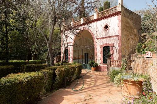 a building with an archway in a garden at Casa Victor Riu in Piera
