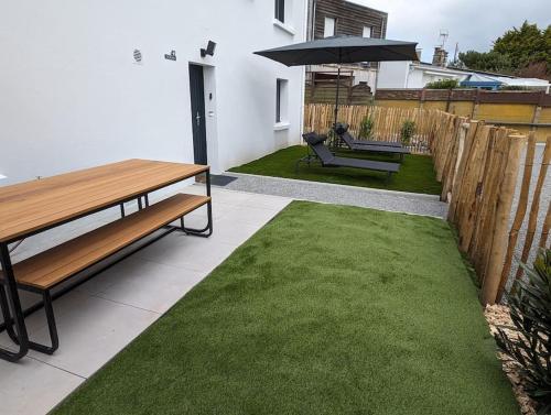 a patio with a bench and an umbrella and grass at 500 m de la plage - Terrasse - 3 chambres in Piriac-sur-Mer