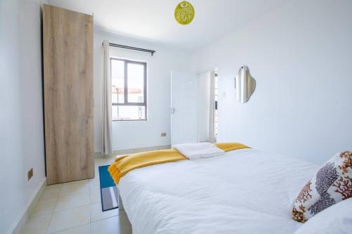 a bedroom with a large white bed and a window at Cosy Nest cribs Nairobi in Nairobi