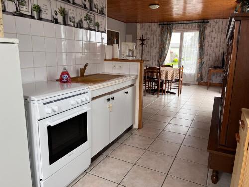 een keuken met witte kasten en een fornuis met oven bij Maison Brem-Sur-Mer in Brem-Sur-Mer