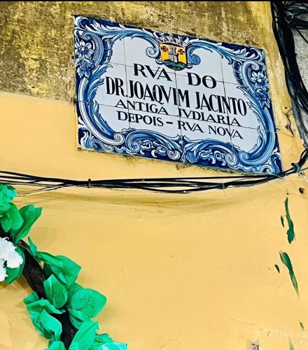 a sign on the side of a yellow wall with a plant at ESTÚDIO 81 junto à Sinagoga in Tomar