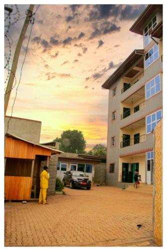 un hombre con un traje amarillo parado al lado de un edificio en Résidences K and D CAMOCO, en Bafoussam