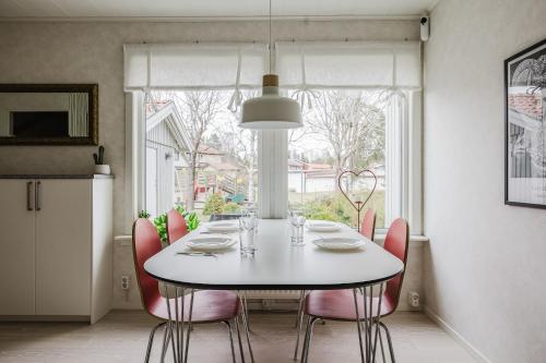 a dining room with a white table and pink chairs at Cozy townhouse 7 beds in Stockholm County in Kungsängen