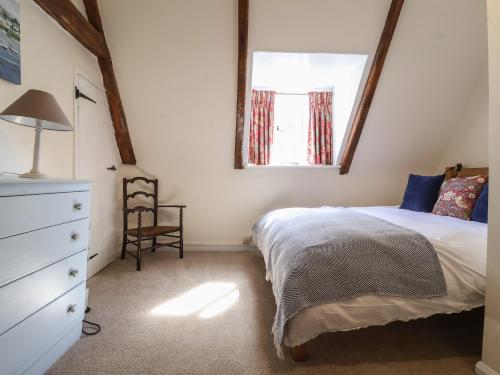 a bedroom with a bed and a window and a chair at 2 The Almshouses in Saxmundham