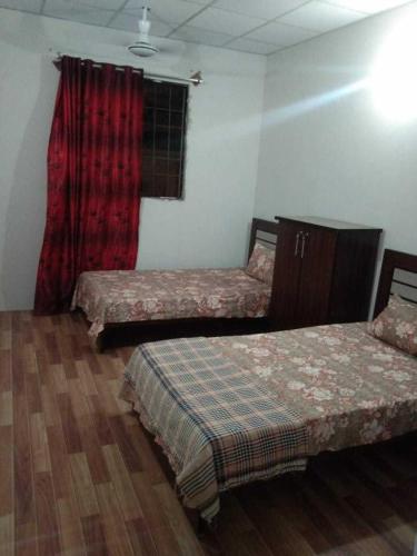 2 letti in una camera con tenda rossa di H.Y Boys Hostel & Rooms for Rent a Karachi