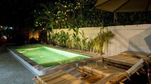 a swimming pool with two chairs and an umbrella at The White Bay Lombok in Kuta Lombok