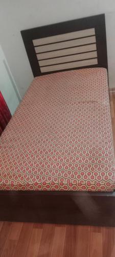 un letto con struttura nera e materasso rosso e bianco di H.Y Boys Hostel & Rooms for Rent a Karachi
