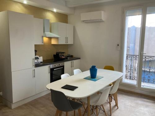 une cuisine avec une table blanche et des armoires blanches dans l'établissement appartement centre historique Meze, à Mèze