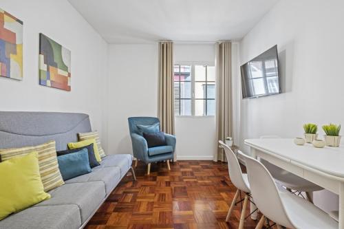 a living room with a couch and a table and chairs at Ribeira do Esmeraldo by Homie in Funchal