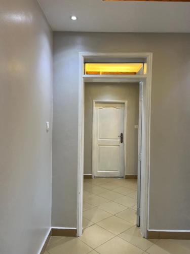 an empty hallway with a white door and a window at CNJ’s Tranquil Haven in Kampala