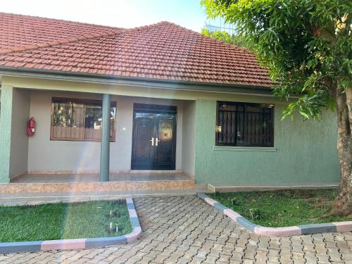 a green house with a blue door and a tree at CNJ’s Tranquil Haven in Kampala