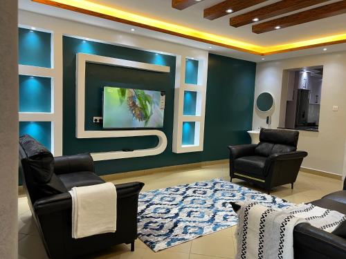a living room with two chairs and a flat screen tv at CNJ’s Tranquil Haven in Kampala