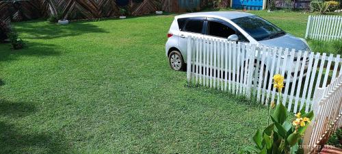 une voiture garée à côté d'une clôture blanche dans l'établissement Kai Suites Kitale, à Kitale
