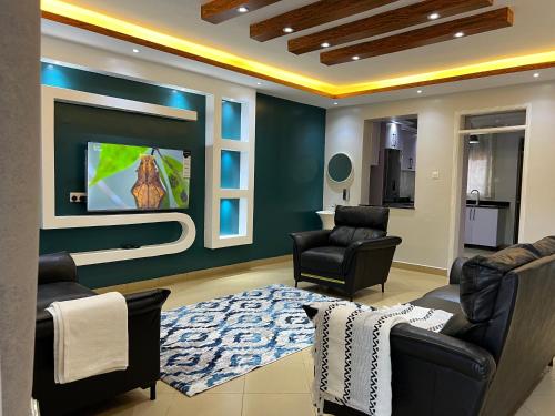 a living room with two chairs and a flat screen tv at CNJ’s Tranquil Haven in Kampala