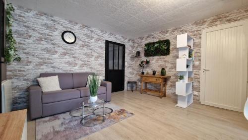 a living room with a purple couch and a brick wall at Appartement Le Welcome in Argelès-Gazost