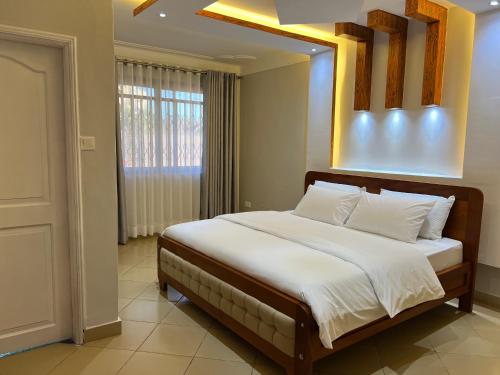 1 dormitorio con 1 cama con espejo encima en CNJ’s Tranquil Haven en Kampala
