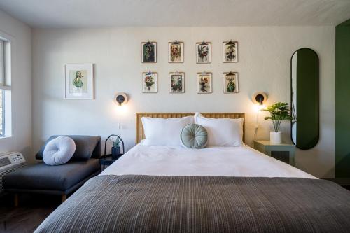 a bedroom with a bed and a chair and pictures on the wall at The Local Motel & Shops in Eugene