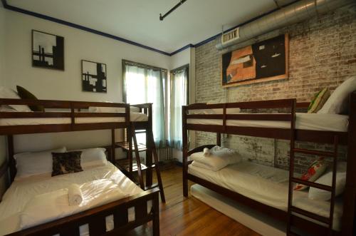 a room with three bunk beds and a brick wall at Michie Hostel in Providence