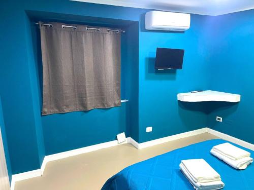 ein blaues Zimmer mit einem TV und einer blauen Wand in der Unterkunft Bed and Breakfast Napoli Centro storico in Neapel