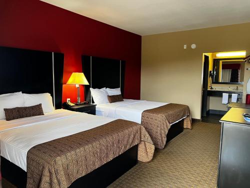 2 Betten in einem Hotelzimmer mit roten Wänden in der Unterkunft Rodeway Inn in Dilley