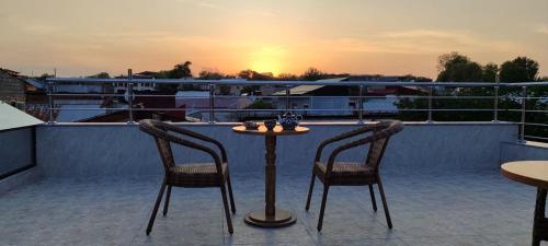 a table and two chairs on a balcony with the sunset at HOTEL MEHRIBON in Samarkand