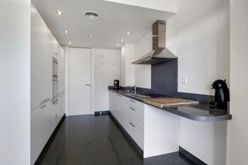 ソトグランデにあるCasa Algo luxe appartement met terras aan zee 133 m2の白いキャビネットとシンク付きの広いキッチン