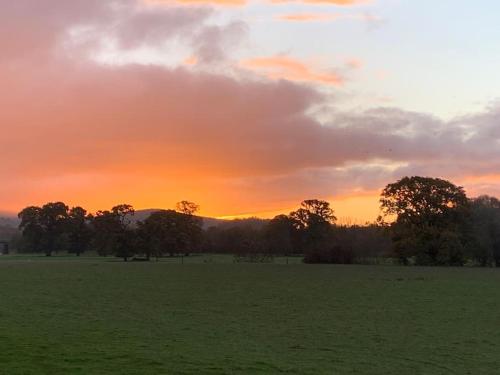 a sunset in a field with trees in a field at Mountain views in the heart of Brecon Town in Brecon