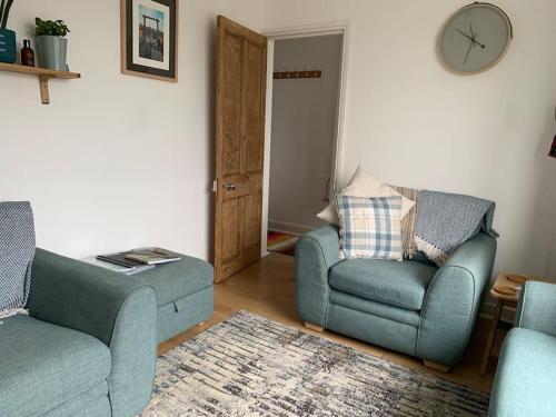 a living room with two chairs and a couch and a clock at Mountain views in the heart of Brecon Town in Brecon