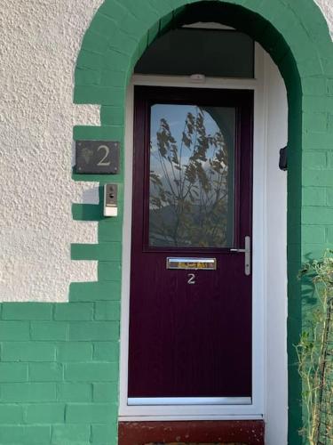 a purple door in a green brick building at Mountain views in the heart of Brecon Town in Brecon