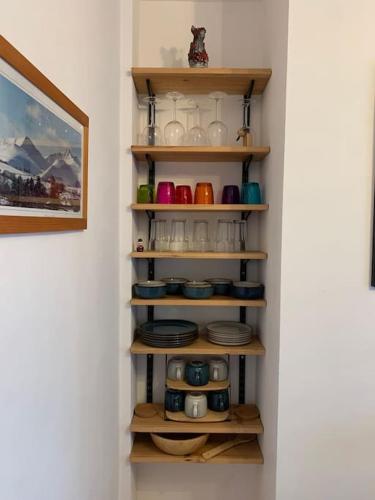 a kitchen shelf with plates and cups and bowls at Mountain views in the heart of Brecon Town in Brecon