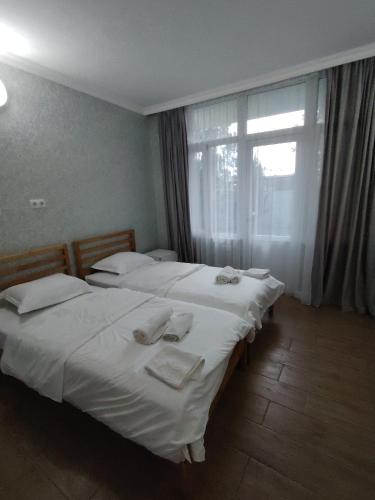 two twin beds in a room with a window at Villa TG in Batumi