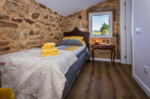 a bedroom with a bed and a stone wall at Casa Lela Dumbria in Dumbría