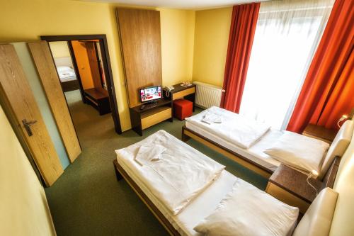 a hotel room with two beds and a television at Hotel Malina-Ski Resort-SKI-IN & SKI-OUT in Ružomberok