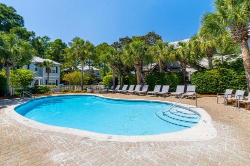 a swimming pool with chairs and palm trees at Cassine Gardens by Panhandle Getaways in Santa Rosa Beach