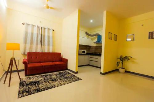 uma sala de estar com um sofá vermelho e uma cozinha em HSR Hillcrest by Newstays em Bangalore