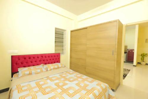 1 dormitorio con 1 cama grande y cabecero rojo en HSR Hillcrest by Newstays, en Bangalore