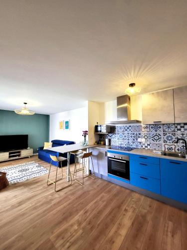 une cuisine avec des placards bleus et une table avec des chaises dans l'établissement Les couleurs de Poteries - avec garage gratuit, à Strasbourg