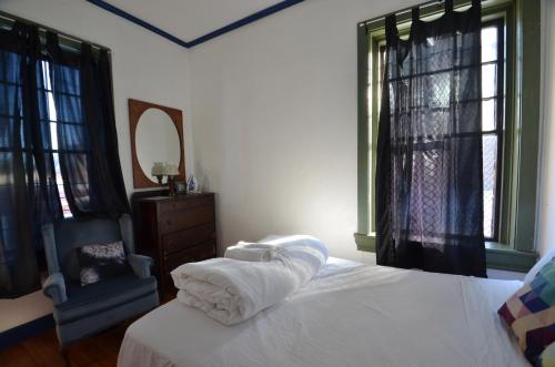 a bedroom with a bed and a chair and windows at Michie Hostel in Providence