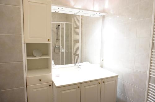 La salle de bains blanche est pourvue d'un lavabo et d'un miroir. dans l'établissement Kustverhuur, Prachtig appartement met uitzicht op zee, Port Scaldis 09-051, à Breskens