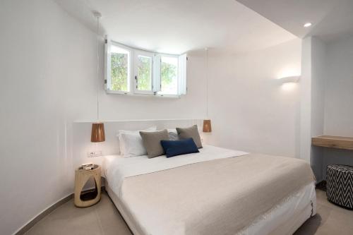 a white bedroom with a large white bed with a window at KAMEO, Antiparos in Andiparos