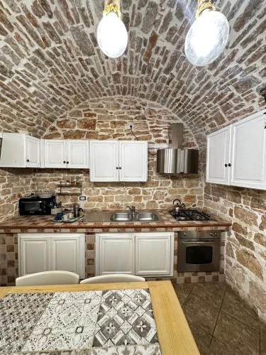 a kitchen with white cabinets and a brick wall at B&B PIETRA VIVA in Sannicandro di Bari