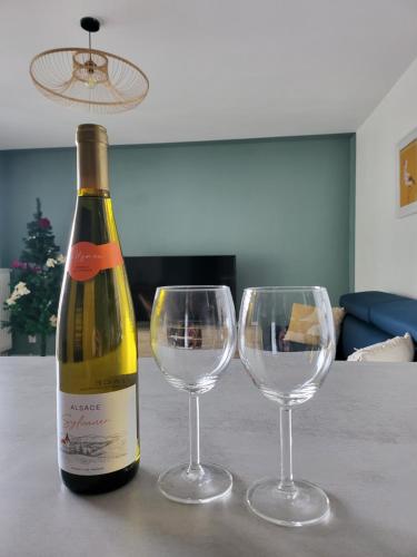 a bottle of wine and two wine glasses on a table at Les couleurs de Poteries - avec garage gratuit in Strasbourg