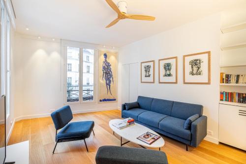 un salon avec un canapé bleu et une table dans l'établissement GuestReady - Appartement moderne et sophistiqué, à Paris
