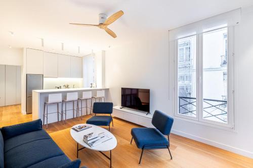 un salon avec un canapé, des chaises et une télévision dans l'établissement GuestReady - Appartement moderne et sophistiqué, à Paris