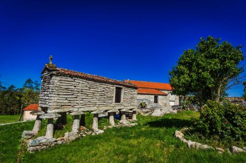 an old stone house in a field with a tree at Casa Lela Dumbria in Dumbría
