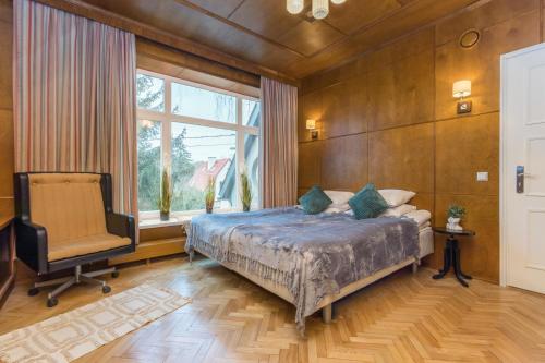 a bedroom with a bed and a chair and a window at Kadriorg by Rikas Hotels in Tallinn