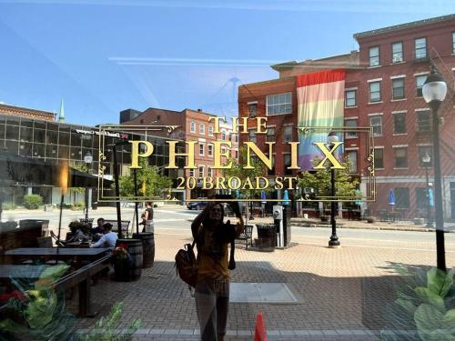 a person standing in front of a sign in a window at The Phenix, Historic DTWN Hotel, Market Square View, King Bed, Room # 400 in Bangor